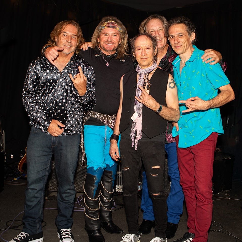 The five members of Rock of Ages together on stage, arms around each other