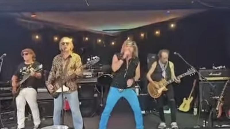 Rock of Ages on stage, the singer at the mic between the guitarists